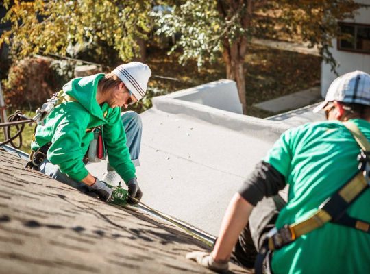 roof repairing crew members on roof of house