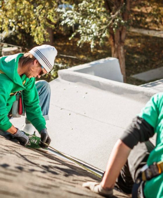 roof repairing crew members on roof of house