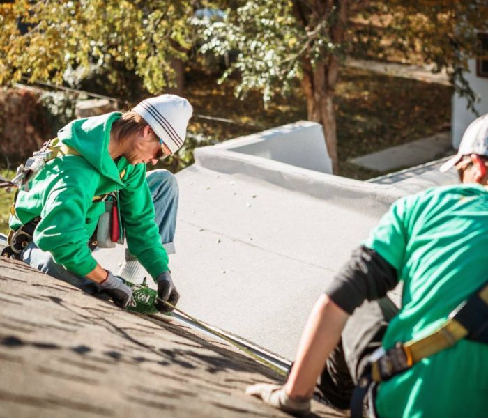 roof repairing crew members on roof of house