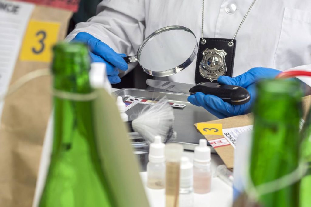 Police investigates with a magnifying glass fingerprint on a knife, conceptual image